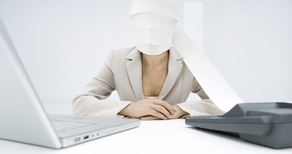 ©Alix Minde/AltoPress/Maxppp ; Professional woman sitting at desk, paper from adding machine wrapped around face